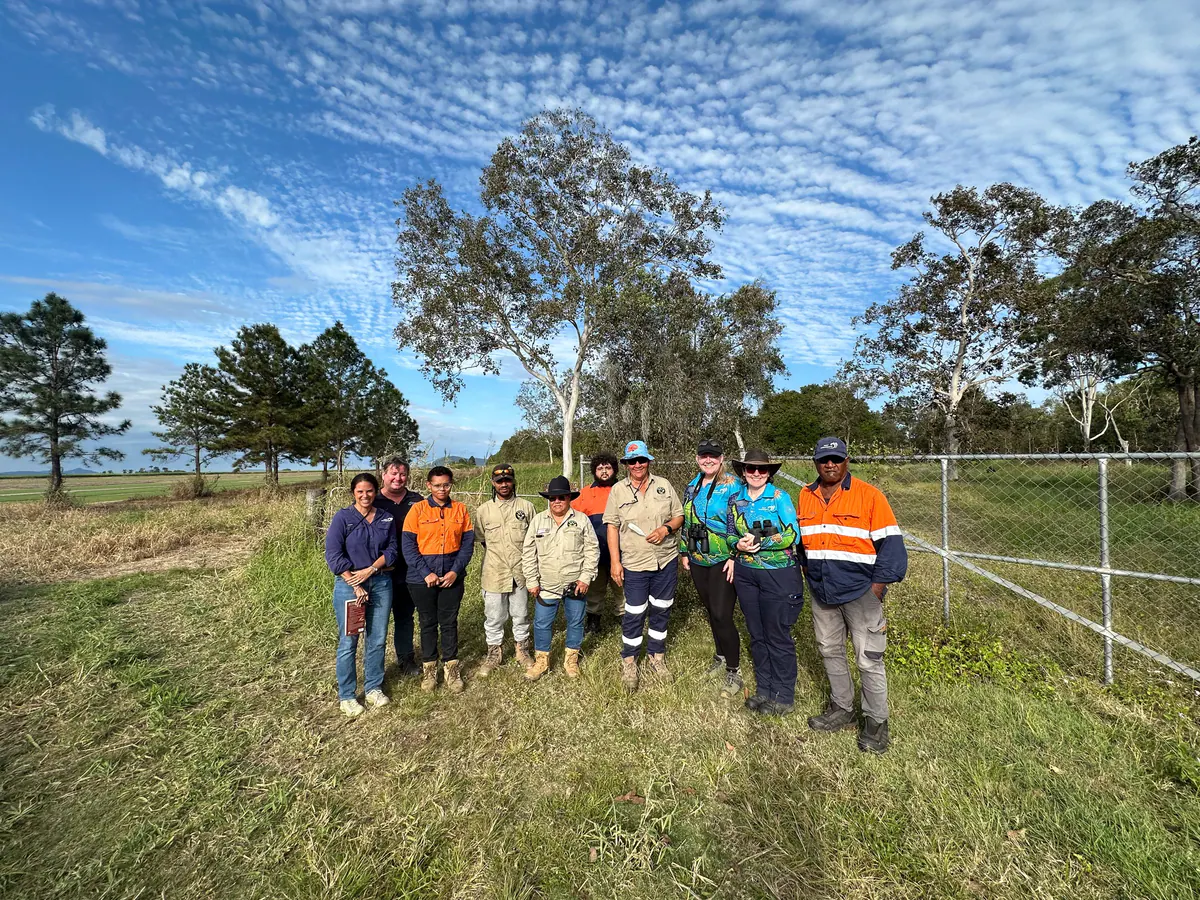 Volunteers beside newly planted native trees on a hillside